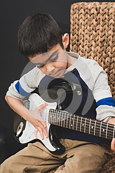 8 year old British Indian boy practices the electric guitar at home.