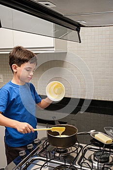 8 year old child pouring condensed milk into the pan and trying to eat it_vertical photo
