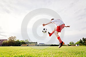 8 years old boy child kicking ball on playing field.