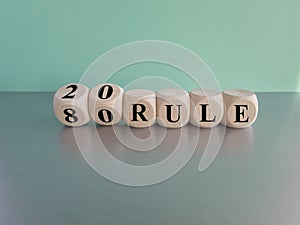 80 on 20 rule symbol. Pareto principle. Turned wooden cubes with words 80 on 20 rule. Beautiful grey table, blue background, copy