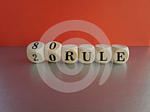 80 on 20 rule symbol. Pareto principle. Turned wooden cubes with words 80 on 20 rule. Beautiful grey table, red background, copy