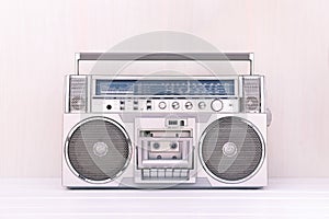 80`s retro cassette radio in silver colour on light wood background