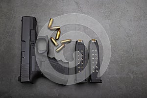 9 mm. Semi automatic pistol handgun and ammunition magazine on old cement texture background