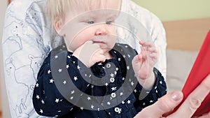 A 9 month old baby in her mother's arms looks at the phone