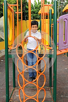 9-year-old dark-skinned Latino boy plays in a playground as a physical activity living in poverty as therapy for ADHD