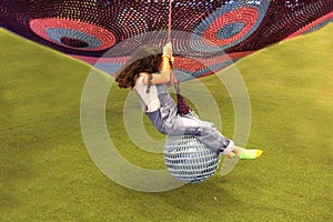 9 year old Latina girl with brunette curly hair plays and has fun on the ball swing as physical activity for good health