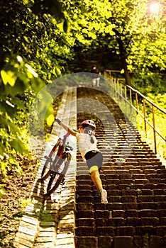 9 years girl bring up for the stairs her bicycle in the sunny day