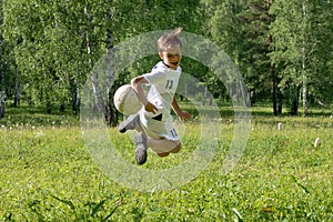 9 years old boy plays soccer. A child kicks a feint with a soccer ball, throws it up