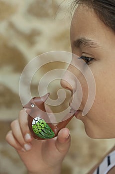 9 years old girl blowing a ceramic water whistle