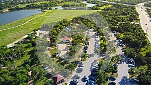 90-acre Brushy Creek Lake Park lush greenery area with busy car parking, sand volleyball courts, scenic picnic pavilion