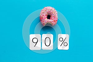 90% off discount - sale concept with bitten donut - on blue background top-down copy space