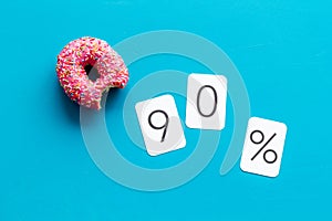 90% off discount - sale concept with bitten donut - on blue background top-down copy space