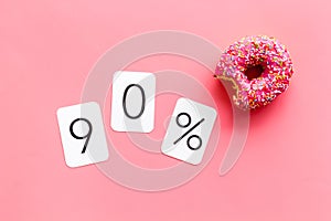 90% off discount - sale concept with bitten donut - on pink background top-down copy space