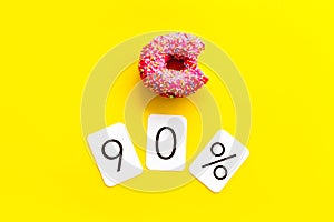 90% off discount - sale concept with bitten donut - on yellow background top-down copy space