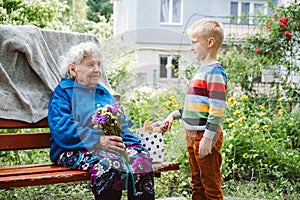 90 year old great-grandmother, grandmother with grandson together. Grandson hugs his beloved grandmother. Kid grandson