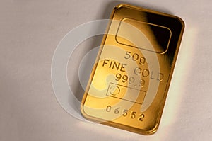 999.9, fineness minted gold bar weighing 50 grams on a gray