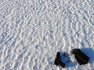 A 9mm pistol and bullets with black gloves scattered in the snow.
