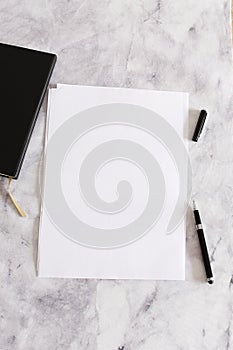 A4 white blank paper on marble background with a pen and notebook, mockup