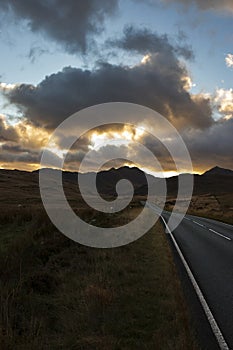 A4086 road, at sunset, heading towards the Llanberis Pass with mount Snowdon in the distance.