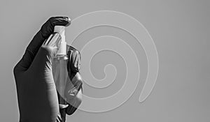 AA hand in a blac rubber medical glove sprays anaesthetic on a grey background. Antibacterial spray for hands antiseptic in hand