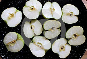 Aapple halves on a black tray fore baking