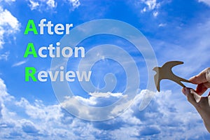 AAR After action review symbol. Concept words AAR After action review on beautiful blue sky clouds background. Wooden bird.