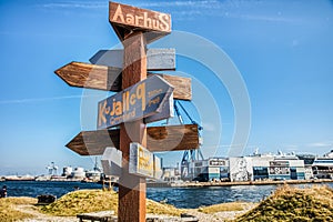 In Aarhus harbour a wooden distance indicator points toward various locations. Decision making, confusion and directional concept