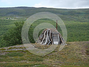 Abadoned Sami hut Goathi in green hills landscape of Abisko National Park. Goahti is Lappish traditional dwelling made from fabric