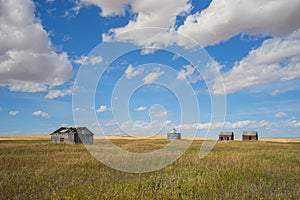 Abandond farm buildings sitting in the praire with a grain silo photo