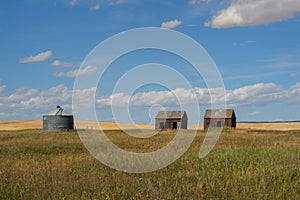 Abandond farm buildings sitting in the praire with a grain silo photo