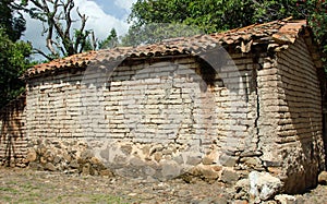 Abandoned adobe brick house with red tile roof
