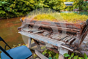 Abandoned aged grand piano covered in the grass near the Vilnia River, Vilnius, Lithuania