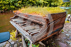 Abandoned aged grand piano covered in the grass near the Vilnia River, Vilnius, Lithuania
