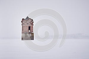 Abandoned ancient water tower in the middle of a frozen river during a snowfall