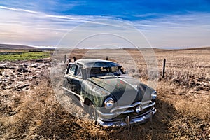 Abandoned antique car in field.