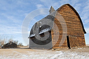 Abandoned barn and collapsed log cabin in winter