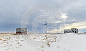 Abandoned Barn, Windmill and House on the Winter Prairie