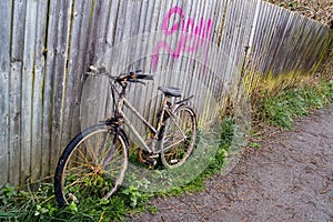 An abandoned bike left on a foot path upright and getting dirty every day.