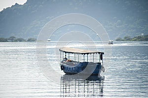 abandoned boat adrift marooned in the middle of water of lake pichola surrounded by aravalli hills in tourist city of