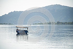 abandoned boat adrift marooned in the middle of water of lake pichola surrounded by aravalli hills in tourist city of