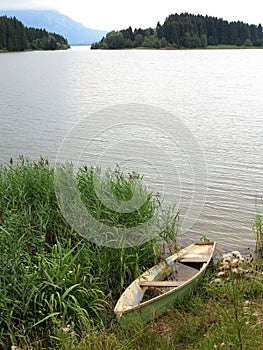 Abandoned wooden boat at shore of lake in mountainous region