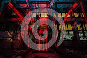 Abandoned brick factory at night. Old rusty brick forming machine and conveyor illuminated by color light. Abstract industrial