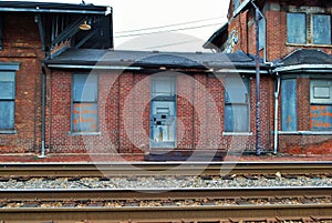 Abandoned brick train depot with tracks and graffiti