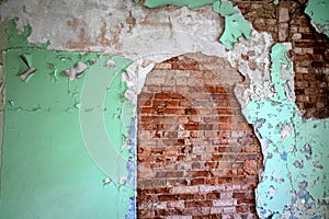 Abandoned brick wall coated with cracked plaster and paint