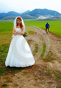 Abandoned bride and groom running away on a bike - funny wedding concept.