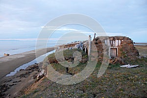 Abandoned broken mud hut at arctic island summer calm sea coast