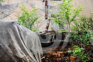An abandoned building with barbed wire, a broken drainpipe and a protective mesh