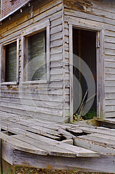 Abandoned building with door showing plants growing from the groungd