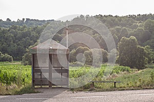 Abandoned bus stop, Yugoslav design, in front of a neglected countryside landscape and a damaged road in Serbia, in a rural area