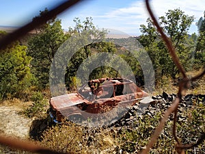 Abandoned car behind a fence in the outskirts of the city